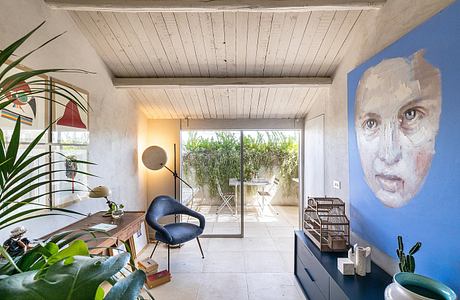 Wooden beamed ceiling, sliding glass doors, indoor-outdoor living space, vibrant artwork.