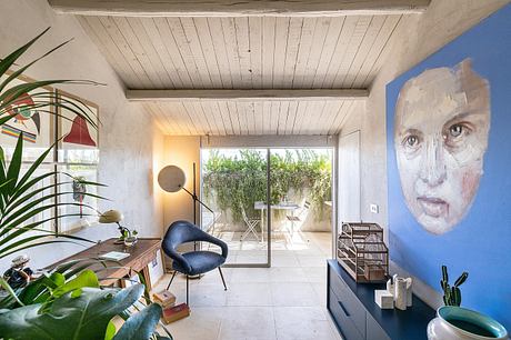 Wooden beamed ceiling, sliding glass doors, indoor-outdoor living space, vibrant artwork.