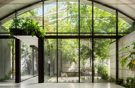 Expansive glass-walled space with lush greenery and a tranquil interior design.