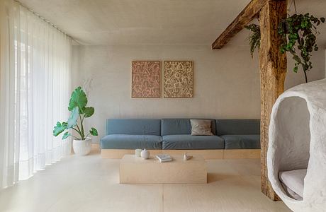 A minimalist living space with wooden beams, neutral tones, and abstract artwork.