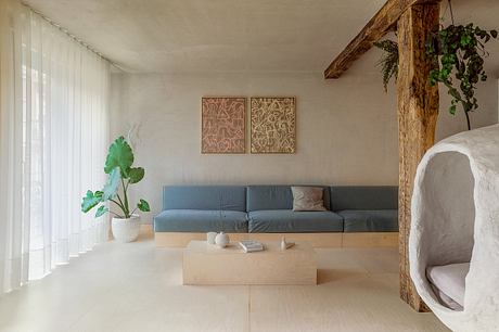 A minimalist living space with wooden beams, neutral tones, and abstract artwork.