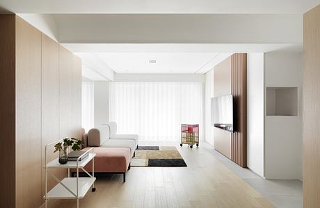 Minimalist living room with natural wood paneling, light hardwood floors, and a modern couch.