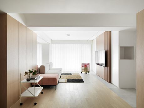 Minimalist living room with natural wood paneling, light hardwood floors, and a modern couch.