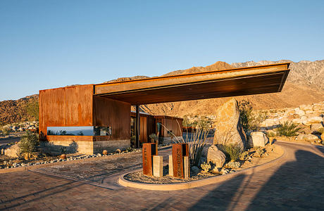 Modern desert architecture with wooden exterior, dramatic mountain backdrop.