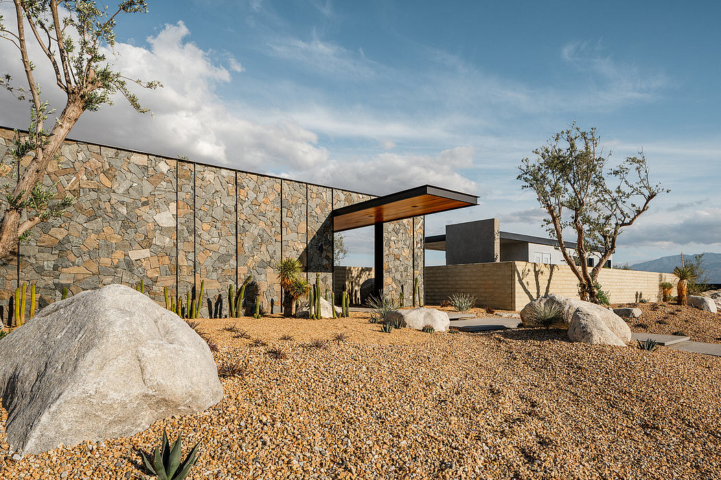 Modern desert home with stacked stone façade, raised walkway, and xeriscape landscaping.