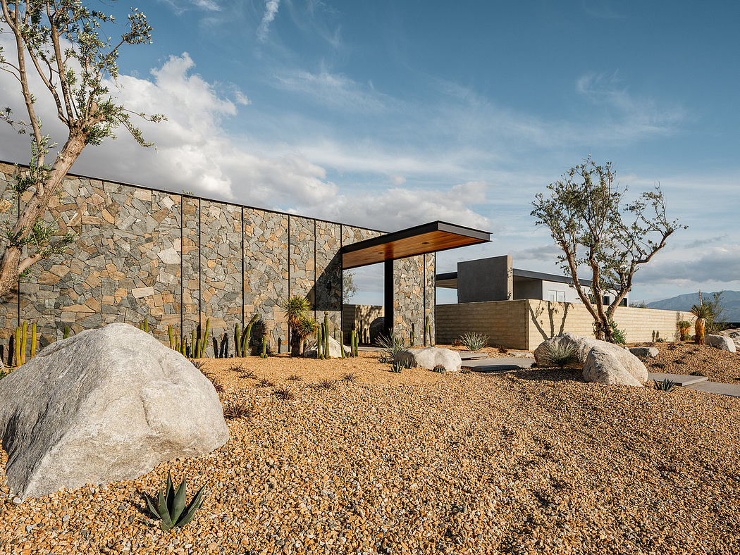 Modern desert home with stacked stone façade, raised walkway, and xeriscape landscaping.