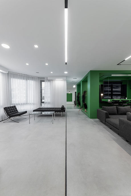 Striking modern interior with stark gray floors, sleek furniture, and bold green accents.