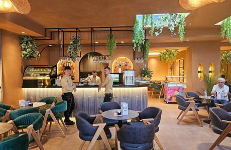 A cozy café with a warm, earthy ambiance, featuring arched doorways, hanging plants, and a sleek bar.