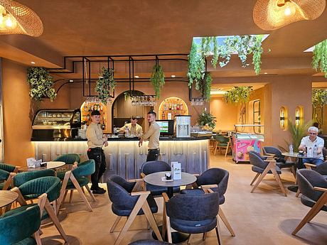 A cozy café with a warm, earthy ambiance, featuring arched doorways, hanging plants, and a sleek bar.