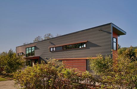 Large modern home with clean lines, wooden accents, and extensive glazing on the facade.