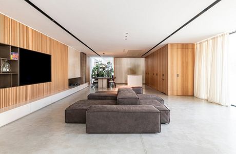 Spacious, minimalist living room with wooden paneling, large sectional sofa, and TV.