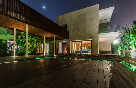 Modern architectural design with wooden beams, stone walls, and a pool surrounded by tropical landscaping.