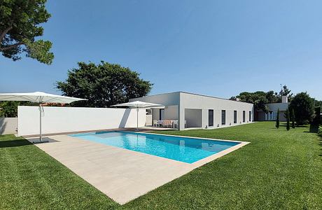 Sleek modern villa with a spacious outdoor pool, surrounded by lush greenery.