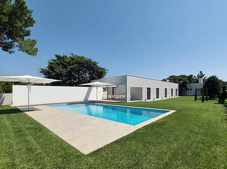 Sleek modern villa with a spacious outdoor pool, surrounded by lush greenery.