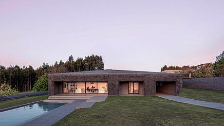 Contemporary single-story house with flat roof, glass walls, and pool in grassy yard.