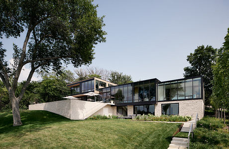 Modern, glass-walled home nestled among lush greenery and with an elevated, stepped design.