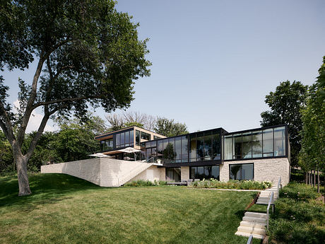 Modern, glass-walled home nestled among lush greenery and with an elevated, stepped design.