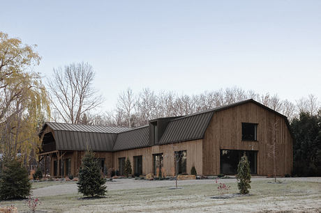 Rustic wooden barn-style building with a gabled roof and metal siding, surrounded by trees.