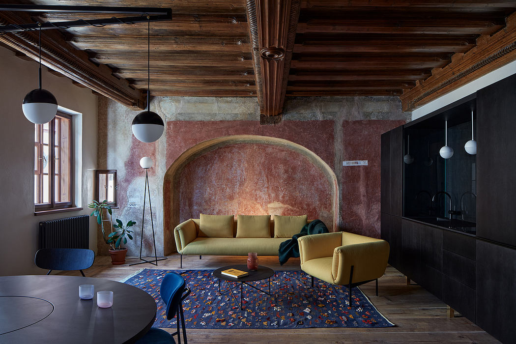 Warm, rustic interior with wood-beamed ceiling, arched stone niche, and patterned rug.