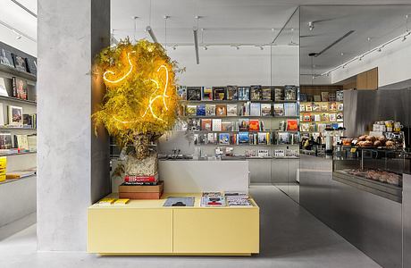 Sleek modern interior with bold neon sculpture, shelves of books, and stainless steel fixtures.