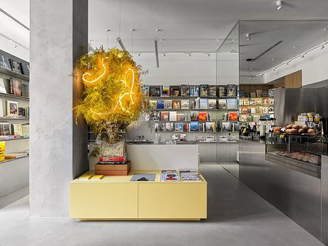 Sleek modern interior with bold neon sculpture, shelves of books, and stainless steel fixtures.