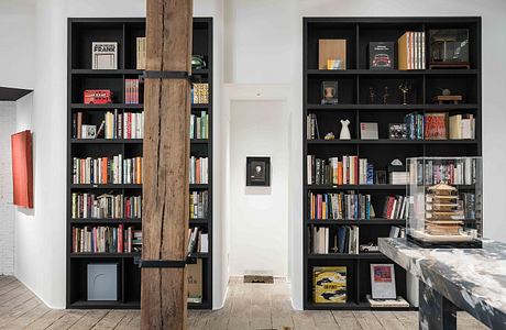 Well-designed, modern space with extensive bookshelves, wooden beam, and a feline resident.