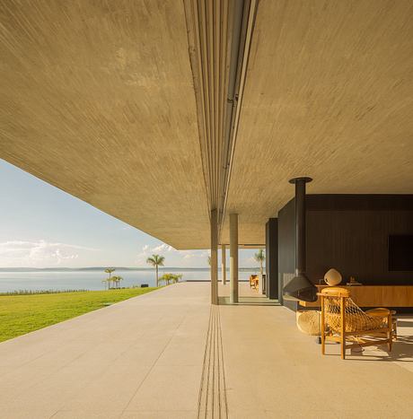 Expansive covered terrace with sleek concrete and wood design overlooking a lush landscape.