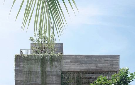 Sleek, modern concrete structure with lush greenery cascading from the balcony.