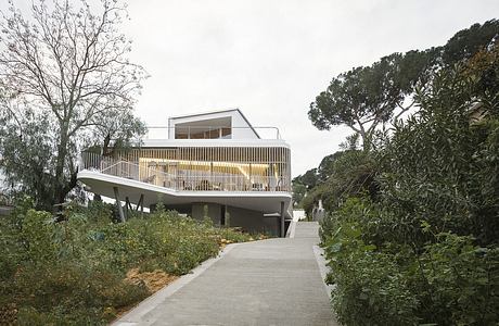 Modern elevated home with expansive balcony and natural surroundings.