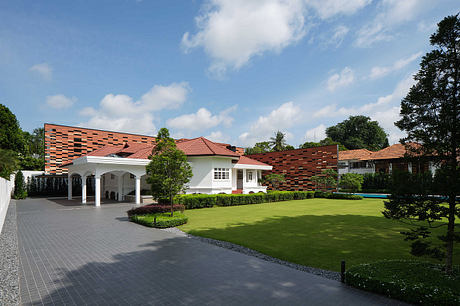 Ornate brick facade, white trim, manicured lawn, and paved entryway in tropical setting.