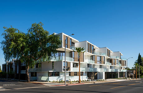 Modern, multi-story apartment complex with clean lines, balconies, and lush vegetation.