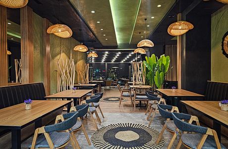 Warm, inviting restaurant interior with bamboo accents, tropical plants, and geometric decor.