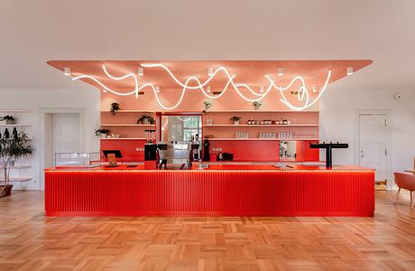 A vibrant red counter with a curved, illuminated overhead feature and sleek interior design.