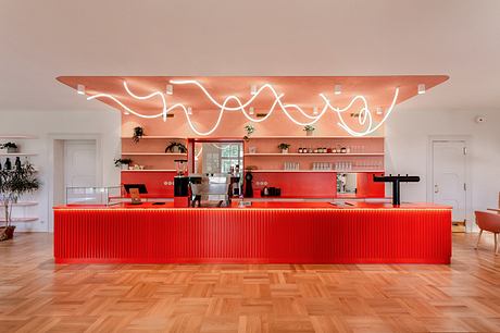 A vibrant red counter with a curved, illuminated overhead feature and sleek interior design.