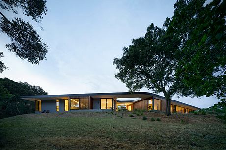 A modern, single-story residential structure with a low-profile roof, large windows, and wood accents.