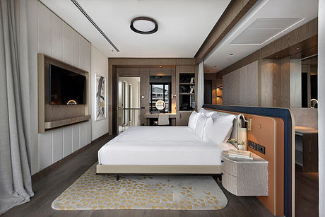 Sleek, modern bedroom with wood paneling, plush bedding, and recessed lighting fixtures.
