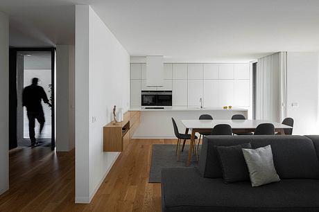 Sleek, modern kitchen and dining area in a minimalist home interior with wood accents.