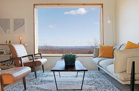 Warm, cozy living room with large windows framing a scenic mountain view and modern furniture.