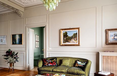 Ornate ceiling, patterned rug, colorful sofa, and framed artwork in elegant room.