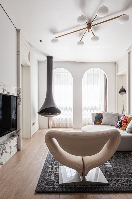 A modern living room with arched windows, a suspended light fixture, and a sculptural chair.