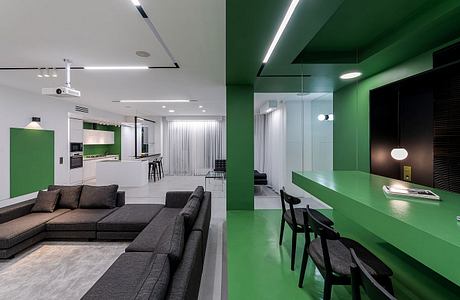 Large open-plan living area with modern, minimalist design featuring bold green accents and sleek lighting.
