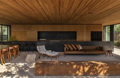 A modern, minimalist lounge area with a cozy, wooden ceiling and contemporary furnishings.