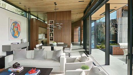 Spacious, modern living area with natural wood tones, large windows, and contemporary furniture.