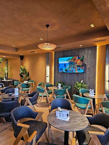 Cozy café interior with hanging pendant light, plush seating, and a large vibrant wall display.
