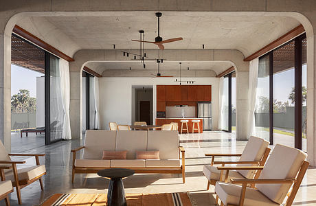 A spacious living area with concrete walls, wooden beams, and contemporary furnishings.