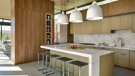 Sleek, modern kitchen with wood-paneled walls, marble countertops, and pendant lighting.