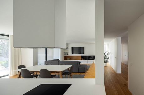 Contemporary open-plan living area with minimalist furnishings, wooden floors, and built-in entertainment unit.