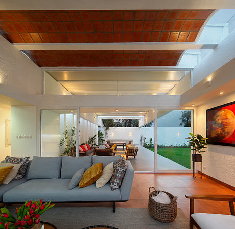 Spacious open-concept living room with brick ceiling, glass walls, and lush outdoor view.