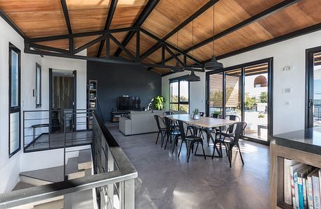 Spacious open-concept living space with a wooden ceiling, metal beams, and concrete floor.