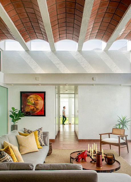 A spacious living room with a vaulted brick ceiling, modern furniture, and artwork.